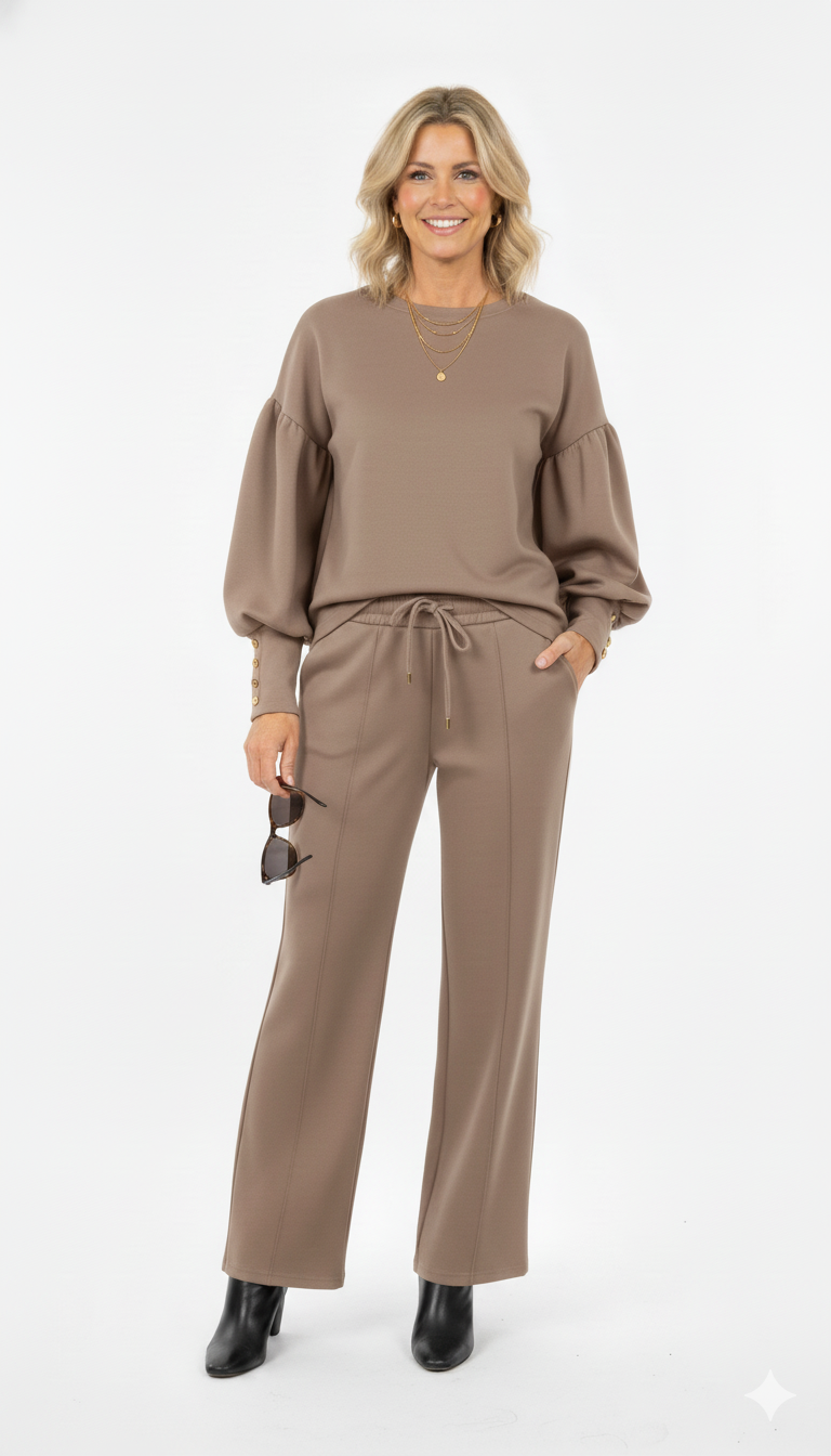 Vrouw draagt taupe dames set met wijde mouwen en rechte broek stijlvolle co-ord outfit met gouden knopen en zwarte enkellaarsjes.