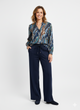 Model draagt een grafische damesblouse in blauw- en bruintinten met donkerblauwe broek.”

“Elegante damesoutfit met printblouse en donkerblauwe broek met elastische taille.”

“Stijlvolle grafische blouse gecombineerd met donkerblauwe damesbroek.”

“Comfortabele en chique damesoutfit met blouse met print en rechte broek.”

“Moderne dameslook: grafische blouse en donkerblauwe broek.”