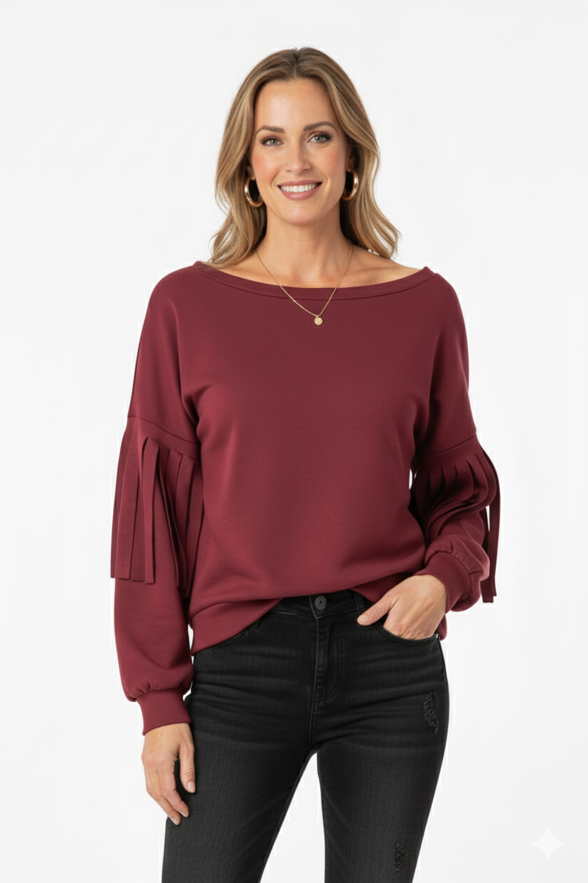 Vrouw met bordeauxrode top met geplooide mouwen, gecombineerd met zwarte broek – elegante damesblouse voor een moderne en stijlvolle look.