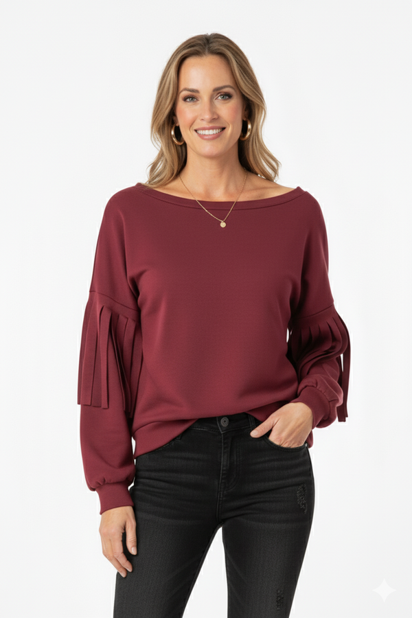 Vrouw met bordeauxrode top met geplooide mouwen, gecombineerd met zwarte broek – elegante damesblouse voor een moderne en stijlvolle look.