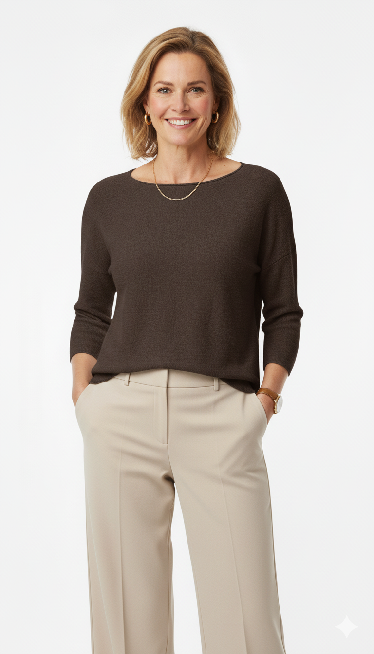 Vrouw met donkerbruine trui met 3/4 mouwen en ronde hals, gecombineerd met beige pantalon – elegante damestrui met comfortabele pasvorm.