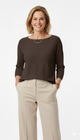 Vrouw met donkerbruine trui met 3/4 mouwen en ronde hals, gecombineerd met beige pantalon – elegante damestrui met comfortabele pasvorm.