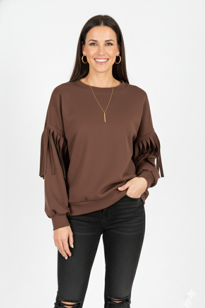 Vrouw met bruine top met geplooide mouwen, gecombineerd met zwarte broek – stijlvolle damesblouse met unieke mouwdetails en moderne uitstraling.