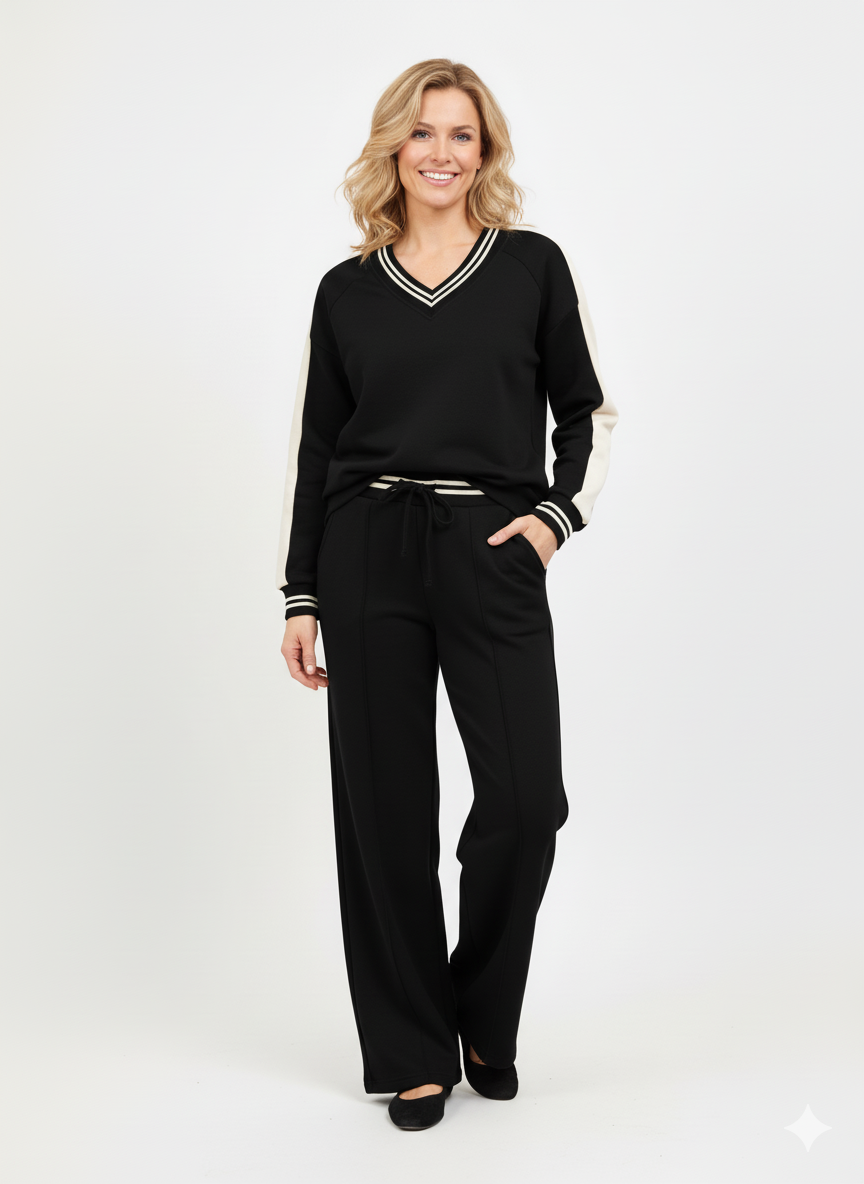 Model draagt een zwarte dames set met V-hals trui en broek met witte details.”

“Sportieve dames set in zwart met contrasterende strepen en bijpassende broek.”

“Trendy zwarte outfit voor dames – V-hals trui met contrastdetails en rechte broek.”

“Zwarte dames set met sportieve uitstraling – ideaal voor casual en athleisure looks.”

“Comfortabele zwarte dames set met V-hals trui en elastische broek.”