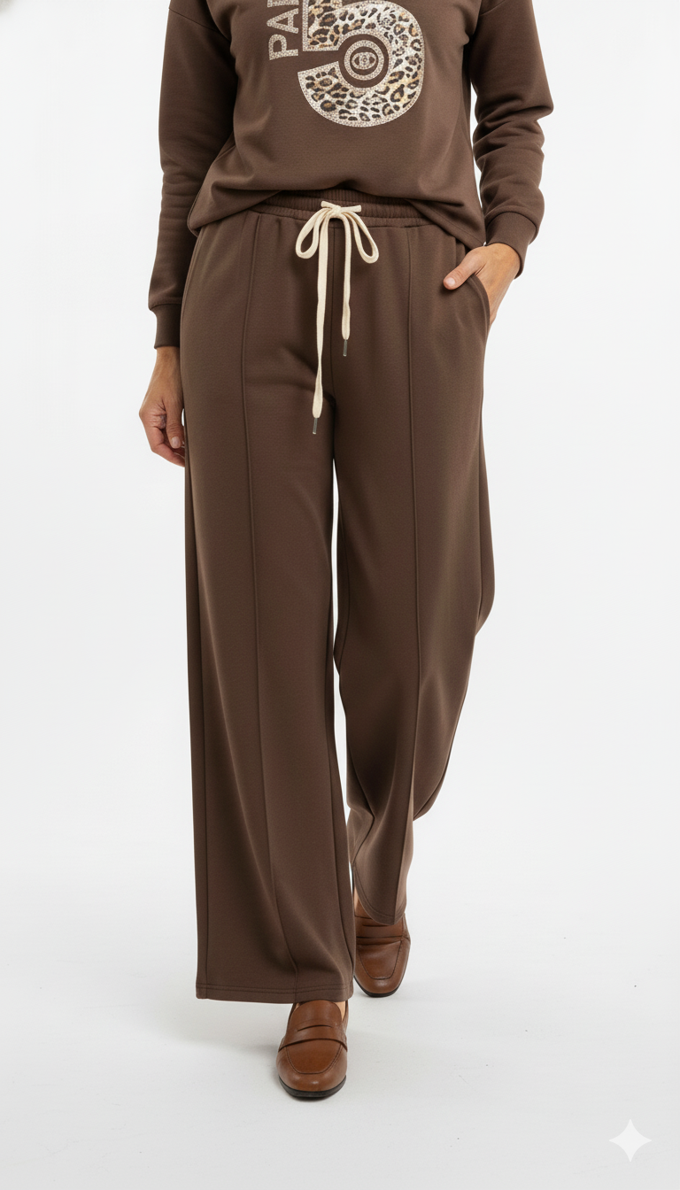 Vrouw draagt chocoladebruine wide leg broek met strikceintuur en bruine loafers – elegante en comfortabele look.