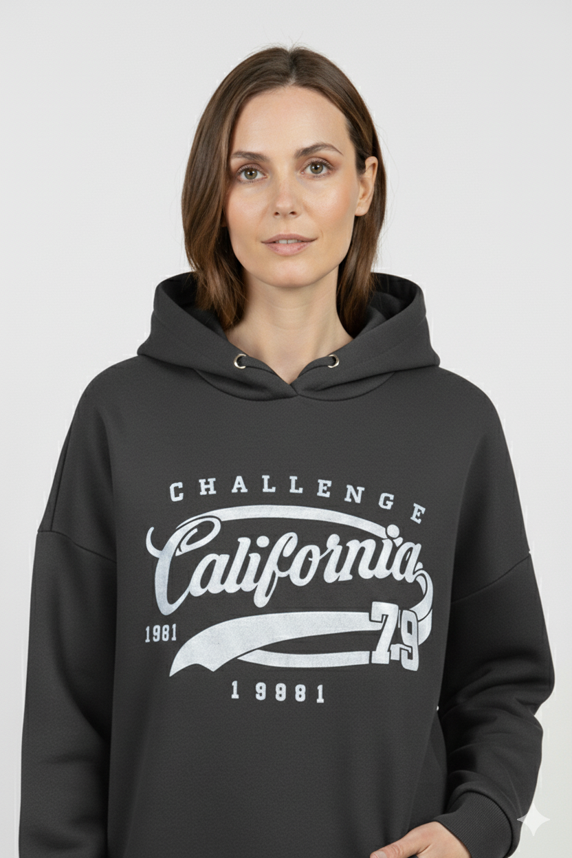 Vrouw met zwarte hoodie met ‘California Challenge 1981’ print – comfortabele damestrui met witte vintage opdruk en sportieve uitstraling.