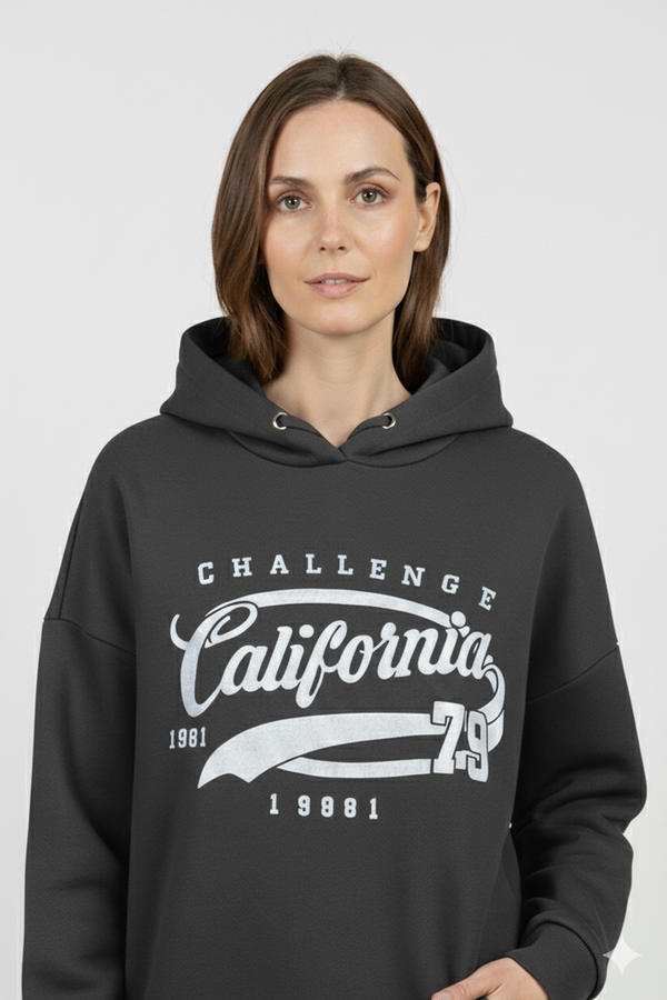 Vrouw met zwarte hoodie met ‘California Challenge 1981’ print – comfortabele damestrui met witte vintage opdruk en sportieve uitstraling.