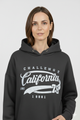 Vrouw met zwarte hoodie met ‘California Challenge 1981’ print – comfortabele damestrui met witte vintage opdruk en sportieve uitstraling.