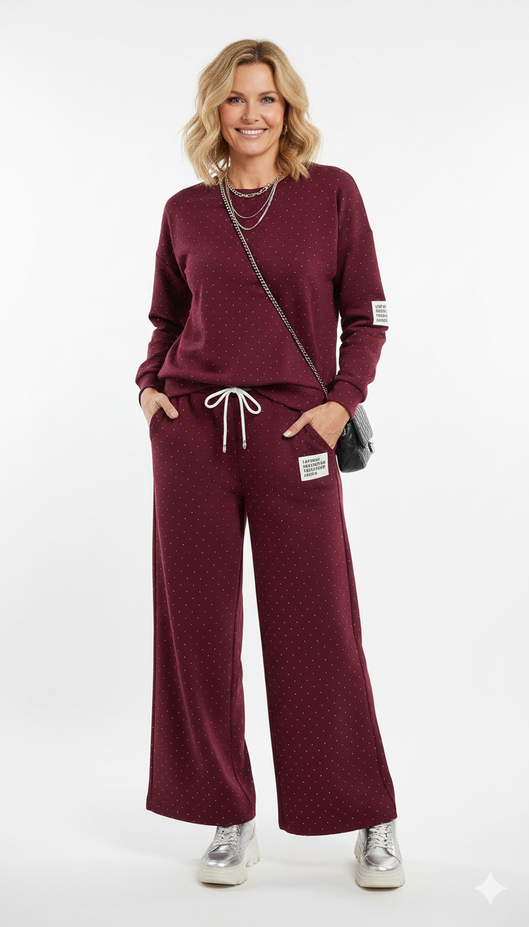 Vrouw draagt bordeaux joggingpak met subtiele stippen comfortabele dames loungewear set met rechte broek en trekkoord.