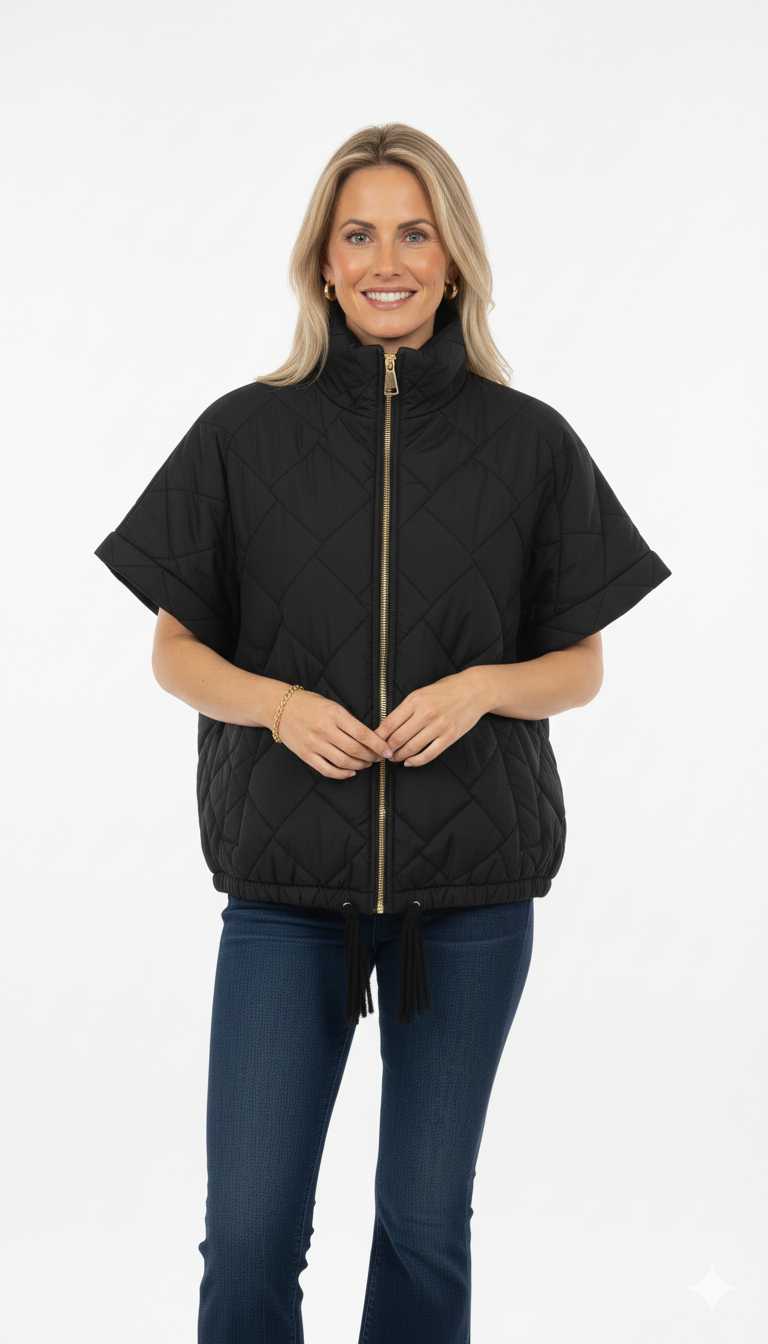 Vrouw draagt zwarte gewatteerde bodywarmer met korte mouwen en gouden ritssluiting – stijlvolle casual look.
