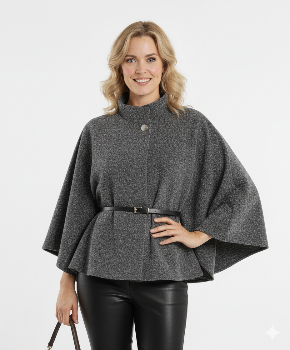 Vrouw draagt grijze dames cape met hoge kraag, knoopsluiting en zwarte ceintuur – stijlvolle cape met luxe uitstraling voor herfst en winter.