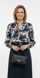 Model draagt blauw-beige abstracte print blouse met V-hals en lange mouwen – elegante damesblouse voor werk en casual chic.