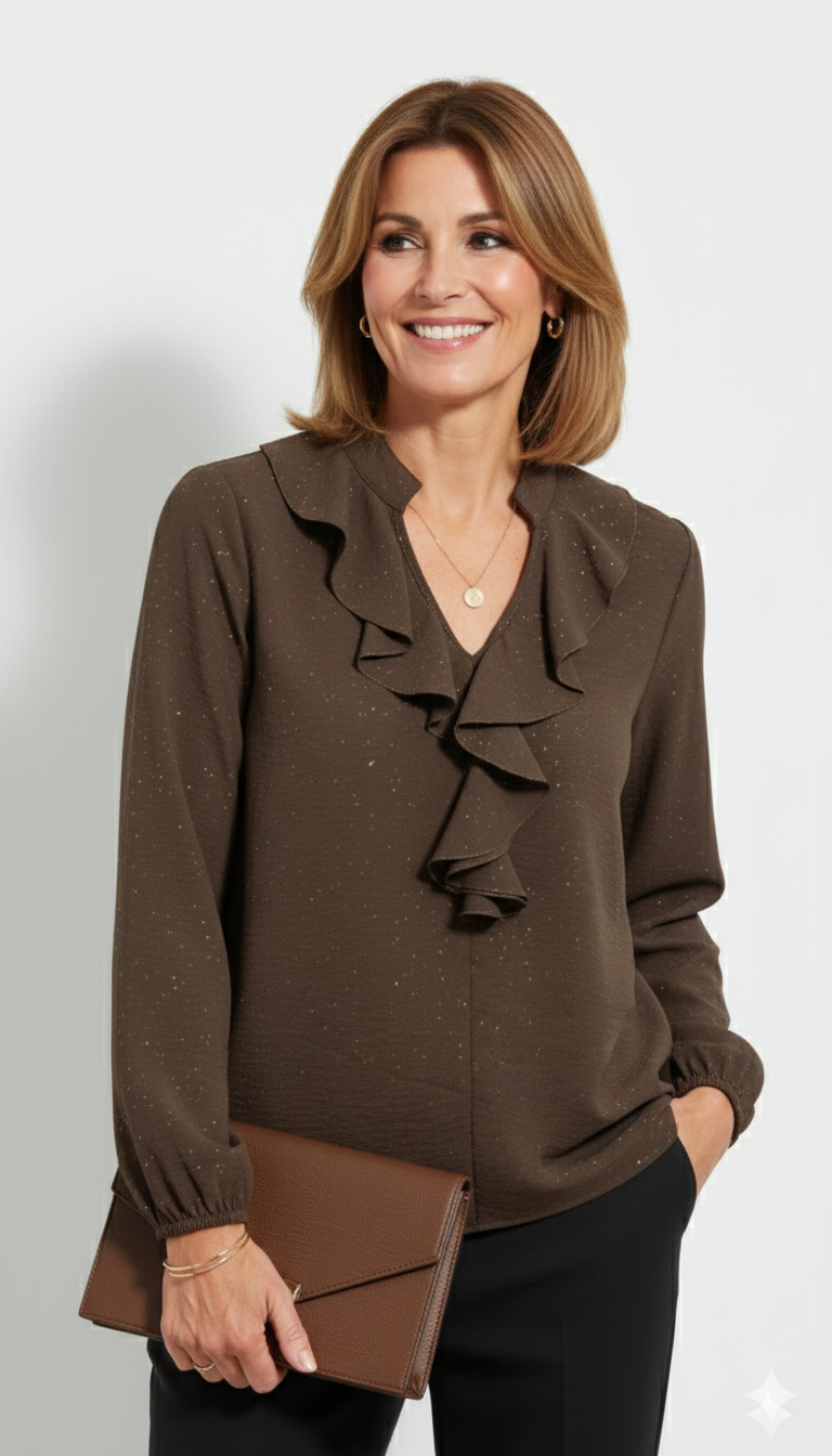Model draagt een bruine glitterblouse met ruches van Blushfashionstore, gecombineerd met een zwarte broek en een bruine clutch.