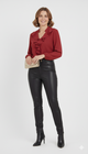 Model draagt een rode blouse met ruches en subtiele glans van Blushfashionstore, gecombineerd met een zwarte broek en gouden sieraden.